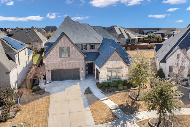 view of front of property featuring brick siding, an attached garage, fence, a residential view, and driveway