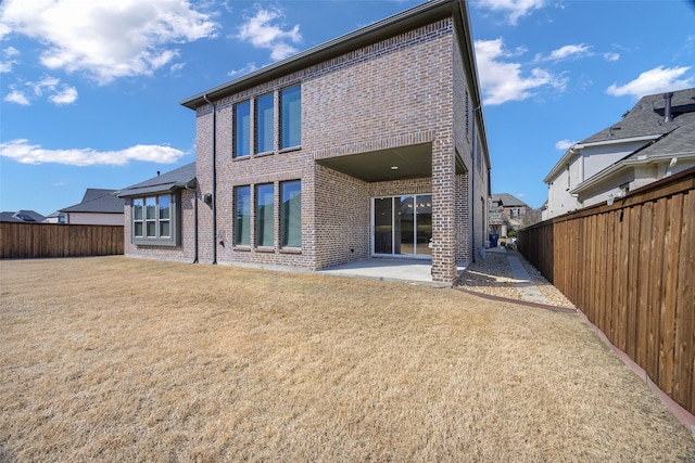 back of house with a yard, brick siding, a patio, and a fenced backyard