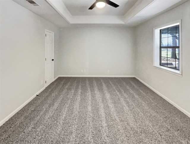 carpeted spare room featuring ceiling fan, baseboards, visible vents, and a raised ceiling