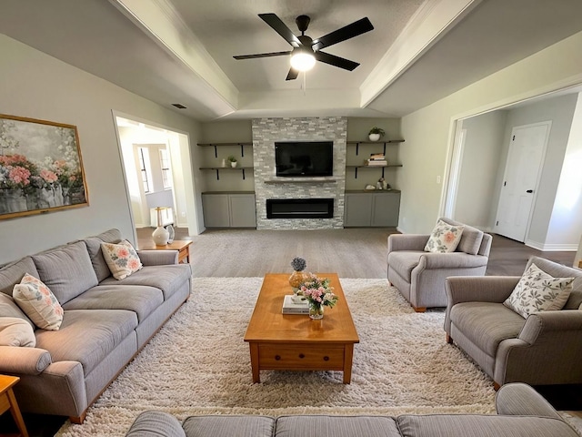 living room featuring a fireplace, wood finished floors, a ceiling fan, baseboards, and a raised ceiling