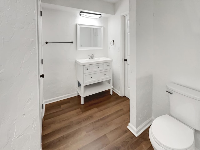 bathroom featuring baseboards, vanity, toilet, and wood finished floors