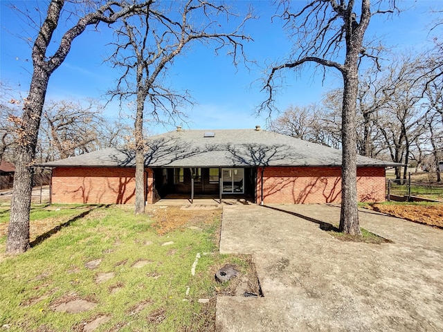 view of front of house featuring driveway, brick siding, roof with shingles, and a front lawn