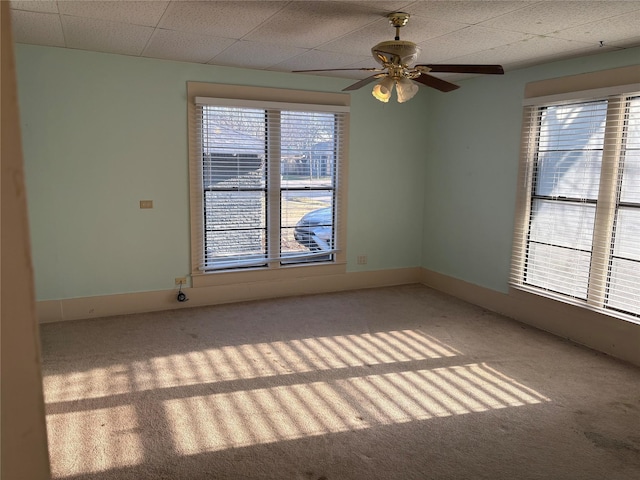 unfurnished room featuring carpet floors, a drop ceiling, baseboards, and a ceiling fan