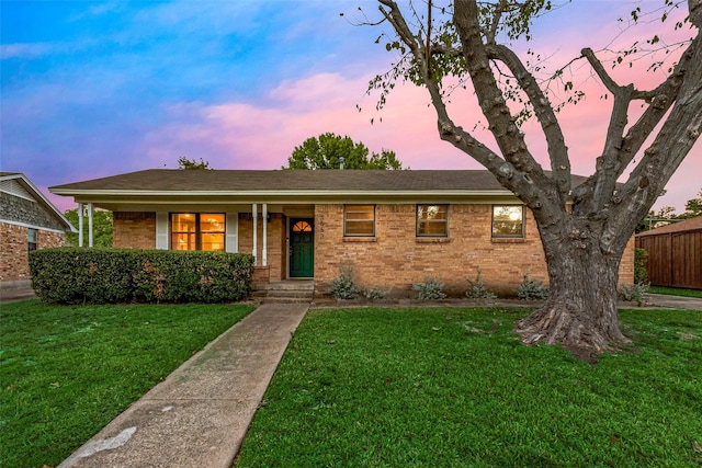 single story home with covered porch, brick siding, a lawn, and fence