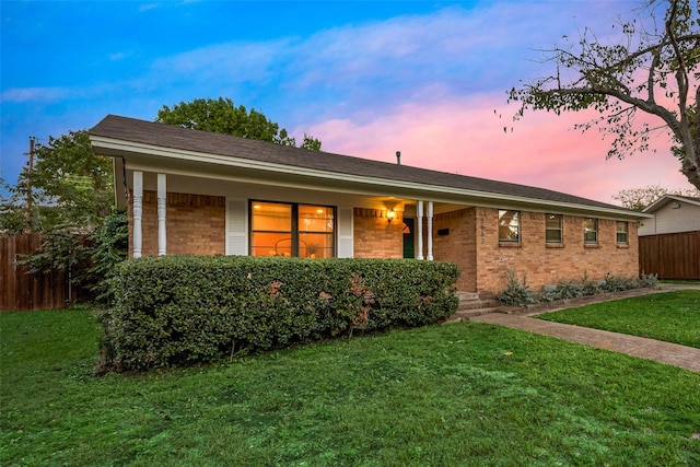 ranch-style home with brick siding, a front yard, and fence