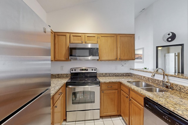 kitchen featuring light stone counters, light tile patterned floors, appliances with stainless steel finishes, and a sink