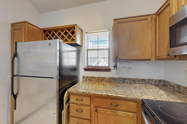 kitchen featuring light stone countertops, appliances with stainless steel finishes, and brown cabinetry