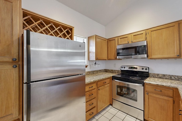 kitchen featuring light tile patterned floors, light stone counters, lofted ceiling, and appliances with stainless steel finishes