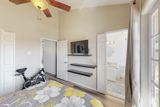 bedroom with wood finished floors, a towering ceiling, and connected bathroom