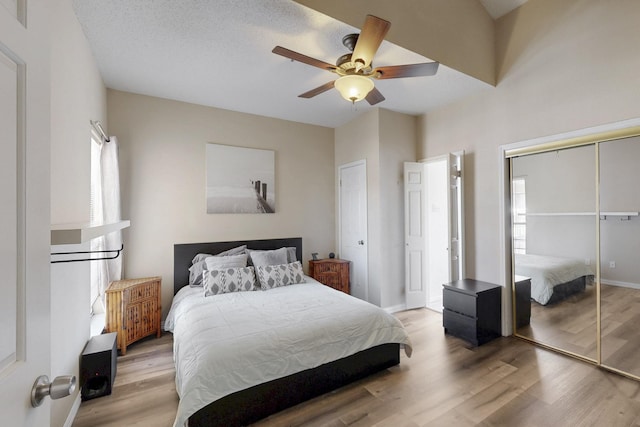 bedroom with a closet, light wood-style flooring, baseboards, and a ceiling fan