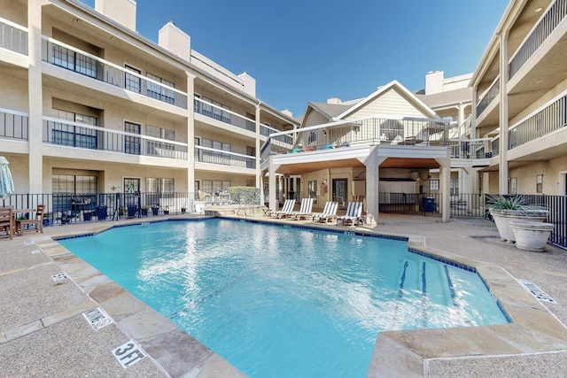 community pool with a patio and fence