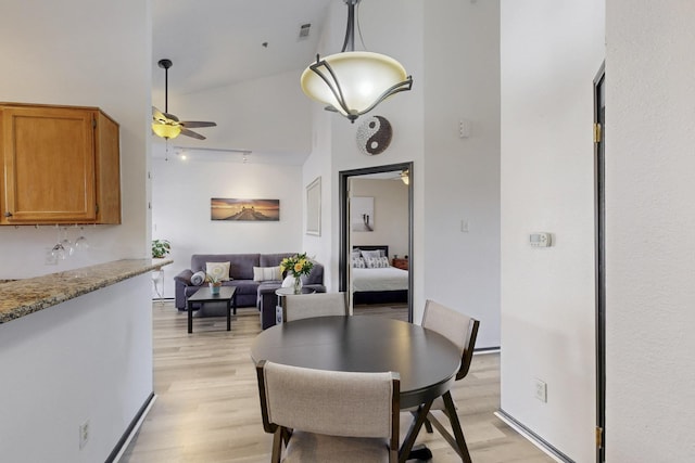 dining space with a ceiling fan, light wood-type flooring, and a towering ceiling