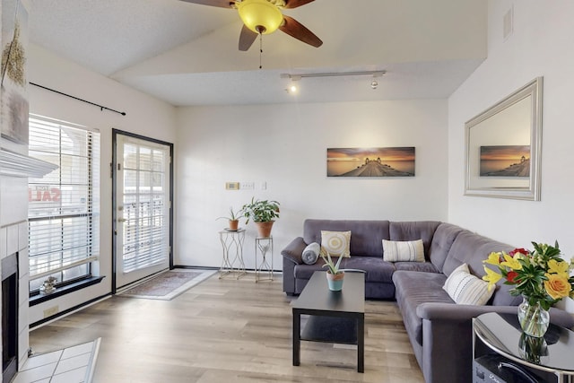 living area with visible vents, light wood finished floors, ceiling fan, rail lighting, and a tiled fireplace