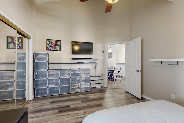 bedroom featuring a high ceiling, wood finished floors, and a ceiling fan