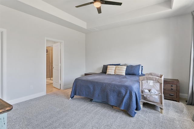 carpeted bedroom featuring ceiling fan, a raised ceiling, connected bathroom, and baseboards