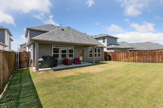 back of house featuring a patio, a shingled roof, a lawn, and a fenced backyard