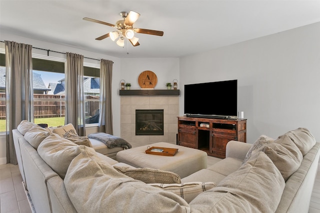 living room featuring ceiling fan and a tiled fireplace