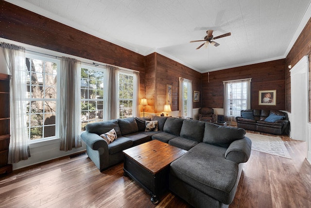 living area with visible vents, crown molding, ceiling fan, wood walls, and hardwood / wood-style flooring