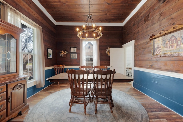 dining area with wood finished floors, an inviting chandelier, wooden ceiling, and wood walls