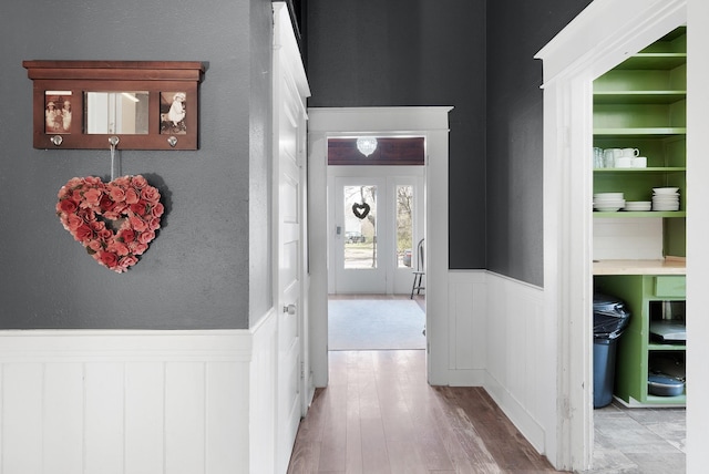 hallway with wood finished floors and a wainscoted wall