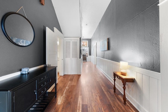 hallway with wood finished floors, wainscoting, and a textured wall