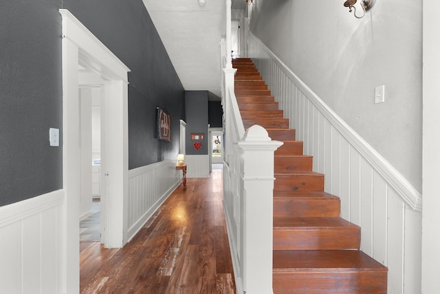 stairs featuring a wainscoted wall and wood finished floors