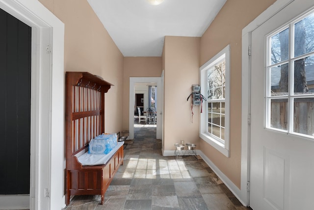 doorway to outside featuring baseboards and stone finish flooring