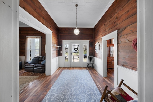 entrance foyer featuring a wealth of natural light, wooden walls, wood finished floors, and crown molding