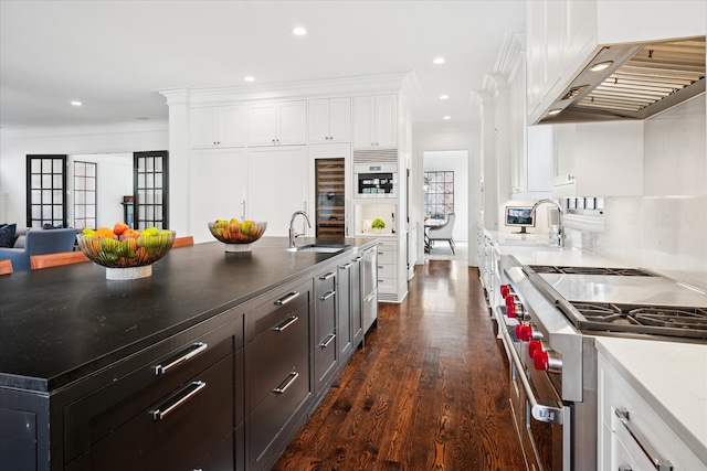 kitchen featuring crown molding, white cabinetry, a sink, high end stove, and under cabinet range hood