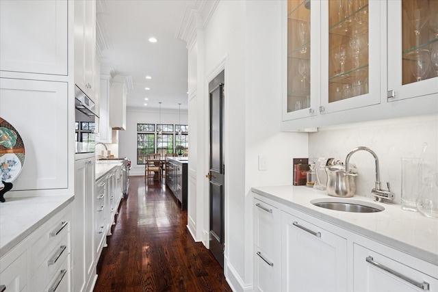 bar featuring crown molding, dark wood-style flooring, backsplash, and a sink