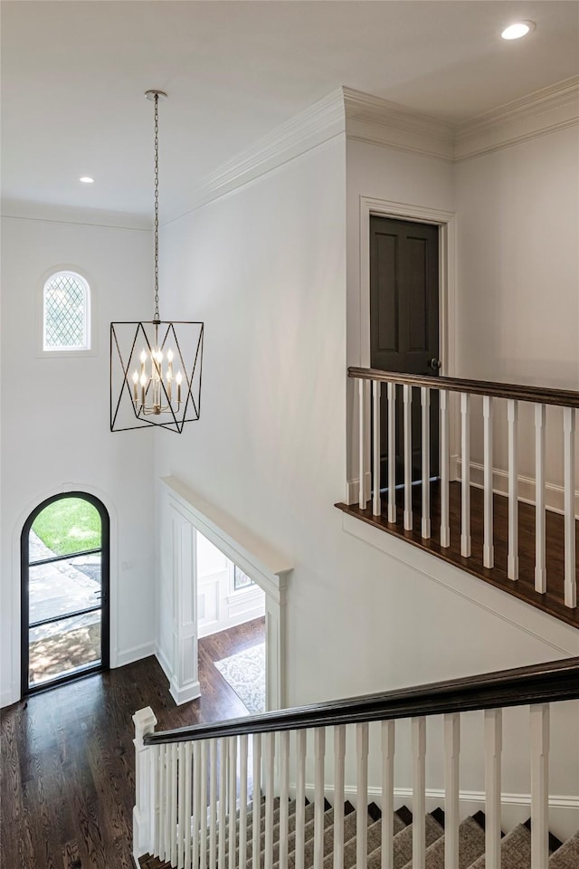 stairway featuring a chandelier, recessed lighting, wood finished floors, baseboards, and ornamental molding