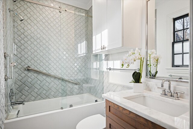 full bath featuring toilet, ornamental molding, combined bath / shower with glass door, vanity, and tile walls