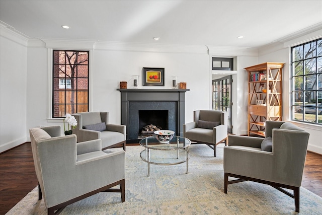 living area featuring ornamental molding, a high end fireplace, baseboards, and wood finished floors