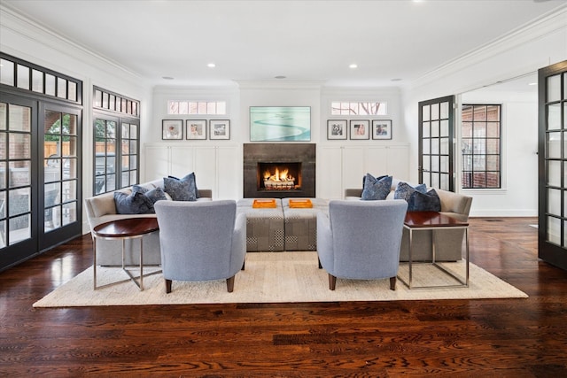 living area with french doors, crown molding, a lit fireplace, and wood finished floors