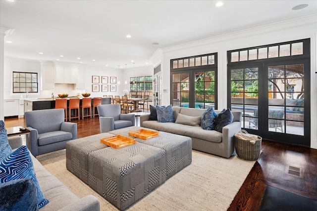 living area featuring ornamental molding, recessed lighting, visible vents, and wood finished floors