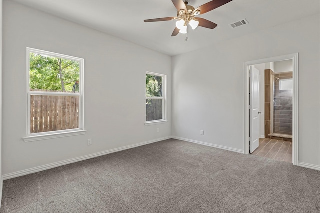 carpeted spare room featuring a ceiling fan, baseboards, visible vents, and a wealth of natural light