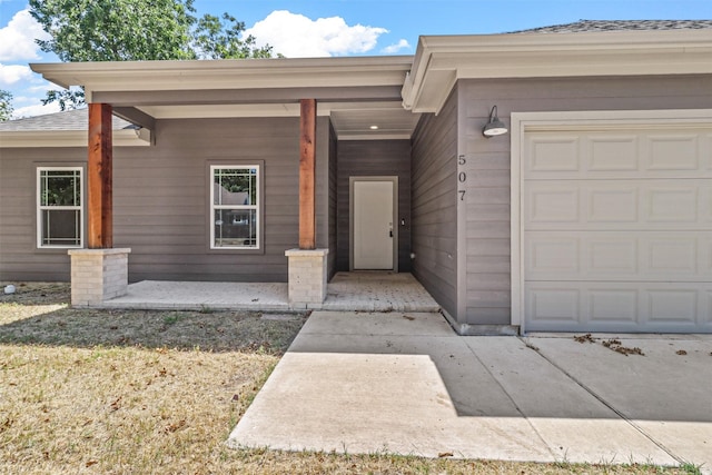 view of exterior entry featuring a garage and covered porch