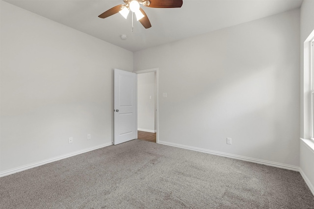 carpeted empty room with a ceiling fan and baseboards