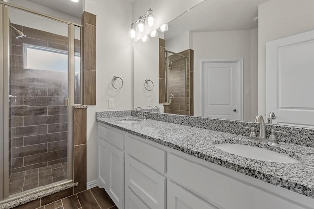 full bathroom featuring double vanity, a stall shower, a sink, and wood finish floors