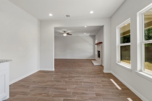 interior space featuring a wealth of natural light, wood finish floors, and a fireplace with raised hearth