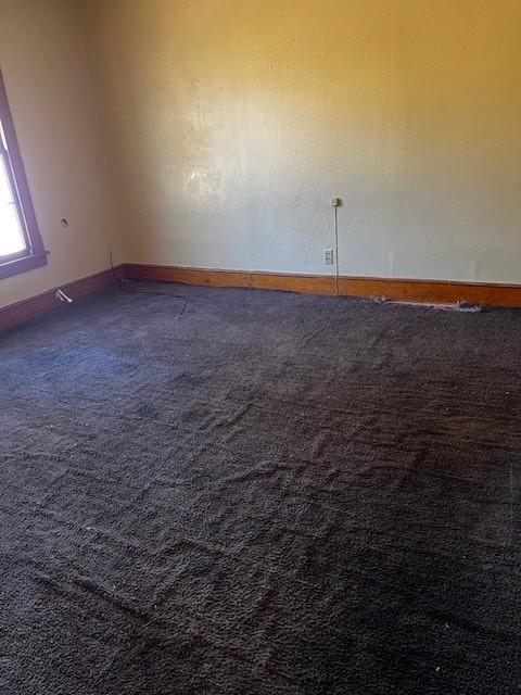 unfurnished room featuring carpet flooring and baseboards