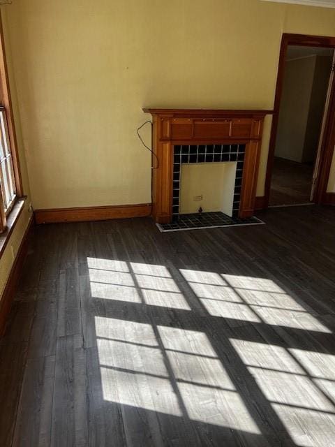 unfurnished living room with baseboards, dark wood-style flooring, and a tile fireplace