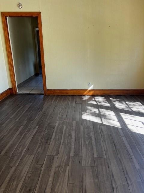 empty room featuring dark wood finished floors and baseboards