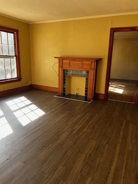 unfurnished living room featuring dark wood-type flooring, a fireplace, baseboards, and ornamental molding