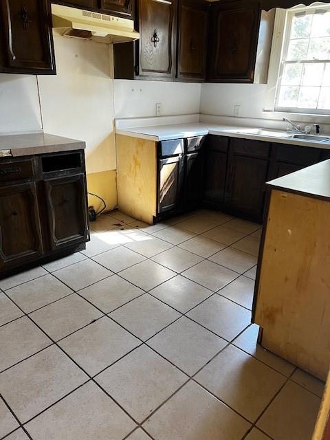 kitchen with light tile patterned floors, light countertops, a sink, and under cabinet range hood