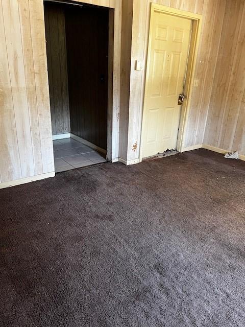 carpeted spare room with wood walls and baseboards