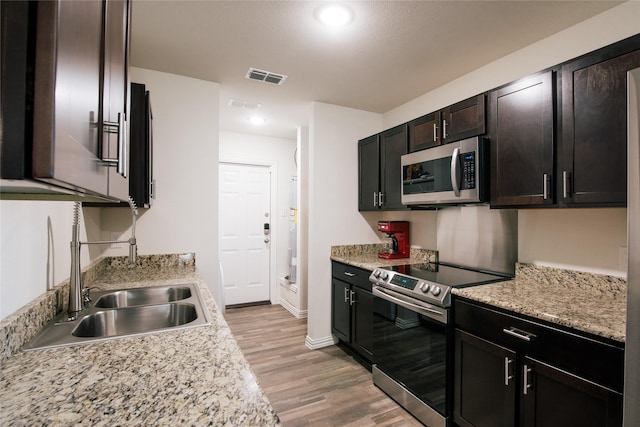 kitchen featuring stainless steel appliances, light countertops, visible vents, light wood-style floors, and a sink