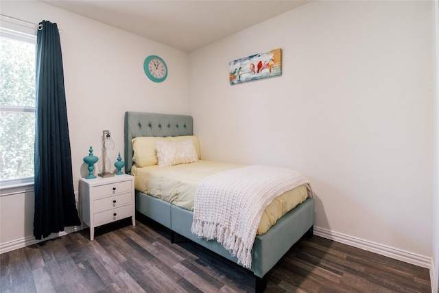 bedroom featuring multiple windows, baseboards, and wood finished floors