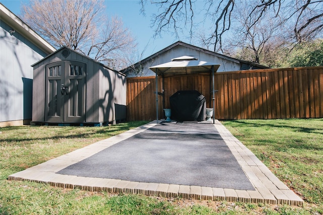 exterior space featuring an outbuilding, driveway, a storage unit, and a fenced backyard