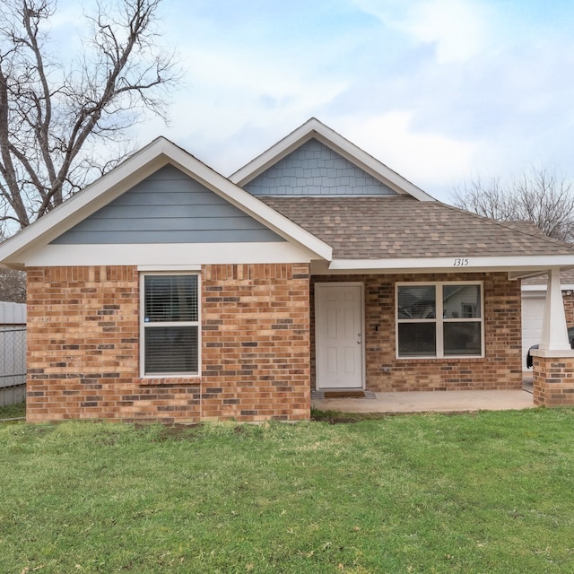 single story home featuring brick siding, a shingled roof, and a front lawn